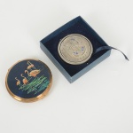 DIVERSOS, duas (2) trousses distintas: 1 confeccionada em metal dourado, tampa em polímero ornada comflamingos em policromia, espelho interno, medindo 8 cm diâmetro; 1 confeccionada em metal prateado, tampa relevadacom simbologia egípcia, espelhos internos, placa se soltando, medindo 6,5 cm diâmetro, ambas com sinais de uso, videfoto.