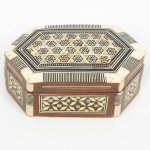 DIVERSOS, uma (1) caixa com marchetaria em madrepérola, marfim ou símile, ébano, etc., geometrizada, formatohexagonal, interior com forração em papel camurça, medindo 12,5 cm comprimento, sinais de uso, vide foto.