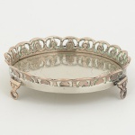 METAL PRATEADO, uma (1) pequena salva com fundo burilado, borda vazada em elementos vegetalistas, pésrelevados em elementos vegetalistas com terminações em garra, medindo 10,5 cm diâmetro, sinais de uso, vide foto.