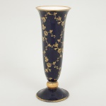 PORCELANA ALEMÃ, um (1) vaso floreiro no formato de corneto, fuste quase esférico, base em saia (quebrada ecolada), tonalidade azul cobalto, ornamentação vegetalista a ouro, manufatura LINDNER, Kueps Bavária, Made inGermany, medindo 27,5 cm altura, sinais de uso, vide foto.