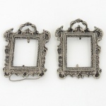FOTOGRAFIA, par (2) porta-retratos, confeccionados em metal prateado, ornamentação relevada em volutas,medindo 8,5 x 6,5 cm, faltam o vidro e o suporte, sinais de uso, vide foto.