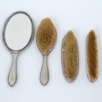 METAL PRATEADO, conjunto com quatro (4) itens: 1 espelho de mão e 3 escovas, ornamentação relevada emperolados, punção da marca WOLFF (tradição desde 1894), medindo a maior peça 27,5 cm comprimento, sinais de uso,vide foto.