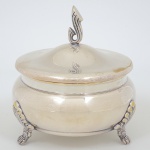 METAL PRATEADO, uma (1) bomboniere com tampa, pés de bicho, pega da tampa colada, medindo 15 cmdiâmetro, sinais de uso, vide foto.