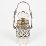 PRATA ALEMÃ, uma (1) pequena cesta com alça vazada em elementos vegetalistas, puncionada: 800 (teor emmilésimos); coroa e a lua (marca nacional que substituiu as marcas individuais das cidades alemãs, Lei Federal de 16 deJulho 1884, usada a partir de 1886, tornou-se obrigatória em 1 Janeiro de 1888); marca de ourives parcialmente legívelnão identificada, peso somente da prata 32 gr., acompanham 3 frascos acoplados, incolores e translúcidos, tampasfacetadas, altura total até a alça 12 cm altura, sinais de uso, vide foto.