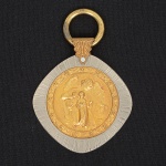ARTE SACRA, uma (1) medalha uniface para adornar berço representando anjo da guarda, confeccionada emmetal dourado e prateado, medindo 6,5 cm diâmetro mais olhal e argola, vide foto.