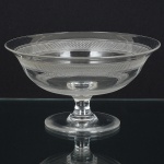 CRISTAL, uma (1) fruteira de pé baixo, incolor e translúcida, fuste cilíndrico, base em bolacha, bojo comlapidação contínua, medindo 20 cm diâmetro, manufatura da CRISTALERIE ROYALE DE SAINT LOUIS (fundada em1586 no vale de Munzthal em Mosela como Verrerie Munzthal; encerrou as atividades em meados do século XVIIdevido a devastação causada na região pela Guerra dos 30 Anos; em 1767 através de Carta Patente concedida pelo ReiLouis XV, retornou as atividades e passou a se chamar Verrerie Royale de Saint Louis; em 1781 M. de Beaufort,descobre a composição do cristal, na época apenas a Inglaterra dominava a técnica do cristal de chumbo, assim a fabricapassou a se chamar Cristallerie Royale de Saint Louis; no século XIX foi a era de ouro da fábrica com váriasintroduções: em 1830 o cristal moldado; em 1834 criou o serviço Trianon; em 1837 introduziu a cor; em 1845 afiligrana, a opalina, o cristal duplo (overlay) e o triplo (double overlay); em 1867 a gravura acidada; em 1989 a Hèrmescomprou a participação acionária da fábrica), medindo 10,5 cm altura, sinais de uso, vide foto.