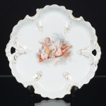 PORCELANA, um (1) prato ornado em policromia representando anjos, recortado e vazado, arremates a ouro, semmarca de manufatura aparente, medindo 18,5 x 18 cm, vide foto.