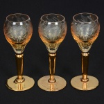 VIDRO, três (3) taças de pé alto para licor, bojo incolor e translúcido com singela lapidação vegetalista, fustequase cilíndrico afinando para baixo e base em bolacha, ambos com douração, medindo 12,5 cm altura, sinais de uso,vide foto.