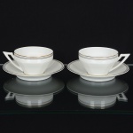 PORCELANA PORTUGUESA, duas (2) xícaras para chá, modeladas em suaves caneluras, faixas nas tonalidadescinza, preto e dourado, manufatura VISTA ALEGRE (fundada em 1824, pelo negociante, lavrador, industrial e político,José Ferreira Pinto Basto, através de alvará concedido por D. João VI, tendo seu fundador associado a fábrica os seus 15filhos, ficando a sociedade denominada Ferreira Pinto & Filhos; cinco anos mais tarde recebe o título real peloreconhecimento de sua arte e sucesso, ficando conhecida como Real Fábrica da Vista Alegre, começou no fabrico devidros enquanto se empenhava em esforços para a produção de porcelana, os primeiros ensaios conseguidos foramimperfeitos denominado loiça de pó de pedra, através de boas relações com a fábrica francesa de Sevres conseguiu asreceitas para o fabrico de porcelana, somente em 1832, por sorte, é encontrado um jazigo de caulim situado em Aveiro,próximo a Ílhavo, a partir desta data o fabrico de porcelana foi se aperfeiçoando em Portugal, 1851 expôs com sucessono Palácio de Cristal em Londres; 1852 D. Fernando II visita a fábrica e encomenda uma baixela completa; 1867recebeu sua primeira premiação na Exposição Universal de Paris; 1880 interrompe a produção de vidros para se dedicarexclusivamente a porcelana; 1964 inauguração do Museu Histórico da Vista Alegre; ainda em funcionamento), videfoto.