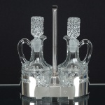 DIVERSOS, um (1) galheteiro com estrutura em aço inox, marca LURALIT, acompanham duas galhetas emcristal, incolores e translúcidas, moldadas em sulcos e bico de jaca, medindo 21,5 cm altura, vide foto.