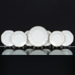 PORCELANA PORTUGUESA, sete (7) itens: 6 pratos para sobremesa, dois deles bicados na borda, medindo 18cm diâmetro; 1 prato raso, medindo 22,5 cm diâmetro, ornados com faixas nas tonalidades cinza, preto e dourado,manufatura VISTA ALEGRE (fundada em 1824, pelo negociante, lavrador, industrial e político, José Ferreira PintoBasto, através de alvará concedido por D. João VI, tendo seu fundador associado a fábrica os seus 15 filhos, ficando asociedade denominada Ferreira Pinto & Filhos; cinco anos mais tarde recebe o título real pelo reconhecimento de suaarte e sucesso, ficando conhecida como Real Fábrica da Vista Alegre, começou no fabrico de vidros enquanto seempenhava em esforços para a produção de porcelana, os primeiros ensaios conseguidos foram imperfeitos denominadoloiça de pó de pedra, através de boas relações com a fábrica francesa de Sevres conseguiu as receitas para o fabrico deporcelana, somente em 1832, por sorte, é encontrado um jazigo de caulim situado em Aveiro, próximo a Ílhavo, a partirdesta data o fabrico de porcelana foi se aperfeiçoando em Portugal, 1851 expôs com sucesso no Palácio de Cristal emLondres; 1852 D. Fernando II visita a fábrica e encomenda uma baixela completa; 1867 recebeu sua primeira premiaçãona Exposição Universal de Paris; 1880 interrompe a produção de vidros para se dedicar exclusivamente a porcelana;1964 inauguração do Museu Histórico da Vista Alegre; ainda em funcionamento), vide foto.