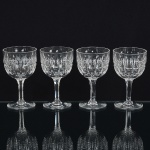 CRISTAL INGLÊS, quatro (4) taças de pé alto, incolores e translúcidas, bojo lapidado em sulcos e dedão, fustehexagonal, base em bolacha, manufatura da Cristaleria STUART, modelo similar ao BACCARAT, medindo 11 cmaltura, sinais de uso, vide foto.