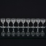 CRISTAL INGLÊS, nove (9) taças de pé alto para licor, incolores e translúcidas, bojo lapidado em sulcos e dedão,fuste hexagonal, base em bolacha, manufatura da Cristaleria STUART, modelo similar ao BACCARAT, medindo 8,5 cmaltura, sinais de uso, vide foto.