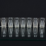 VIDRO, sete (7) copos, incolores e translúcidos, quase cilíndricos, metade inferior lapidada em sulcos verticais ehorizontais, medindo 4,5 cm diâmetro e 7 cm altura, sinais de uso, vide foto.