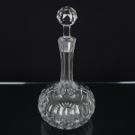 CRISTAL INGLÊS, uma (1) antiga licoreira, incolor e translúcida, lapidada em sulcos e dedão, fundo estrelado,tampa facetada, manufatura da Cristaleria STUART, modelo similar ao BACCARAT, medindo 28,5 cm altura, sinais deuso, vide foto.