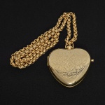 BIJUTERIA, um (1) colar confeccionado em metal dourado, modelo tipo Cartier, acompanha relicário grande noformato de coração, medindo a corrente 73 cm comprimento, o pingente 6 x 6 cm, sinais de uso, vide foto.