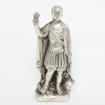 ARTE SACRA, uma (1) imaginária representado Santo Expedito, confeccionada em metal prateado, medindo 10cm altura, vide foto.