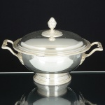 METAL PRATEADO, uma (1) antiga terrina com tampa, ornamentação no padrão Império Napoleônico, comfrisos intercalados por X e folhas, pega da tampa no formato de pinha, manufatura FRACALANZA (tradição desde1884), medindo 26,5 cm diâmetro mais as alças, sinais de uso, vide foto.