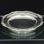 METAL PRATEADO, uma (1) travessa circular, borda reforçada com ornamentação relevada em friosos elaçarotes, manufatura FRACALANZA (tradição desde 1884), medindo 27,5 cm diâmetro, sinais de uso, vide foto.