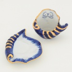 PORCELANA, uma (1) xícara miniatura, modelada no formato de concha, ornamentação pintada a mão natonalidade azul cobalto, arremates a ouro, marca possessória representada pela letra V, medindo 6 cm altura, ideal paracoleção de cristaleira, vide foto.