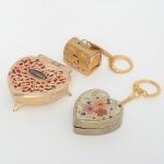 COLECIONISMO, três (3) itens: 1 chaveiro no formato de coração com dispositivo musical parado, medindo 4,5 x4 x 1,5 cm; 1 chaveiro no formato de bau, souvenir de Capri (ilha na Itália), medindo 3 x 2 x 2,5 cm mais a corrente; 1porta joias no formato de coração, souvenir de Los Angeles, medindo 6 x 6 x 2 cm, todos os itens confeccionados emmetal e outros materiais, vide foto.