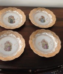 Conjunto de quatro pratos de porcelana bordas dourados em relevo camafeu ao centro pequenos desbotados nos dourados 21 cm.