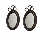 Par de espelhos ovais em madeira patinado de negro e dourado encimado por  laço 35x23.