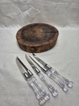 Linda tábua de cortes em tronco de madeira e 5 facas em aço inox com pega em plástico incolor. Medindo a tabua 26cm x 6cm de altura.