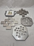 Lote de 5 descansos de panela em metal prateado. Medindo o maior 19cm x 17,5cm.