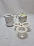 Lote de leiteira, açucareiro em porcelana e 3 porta ovos em vidro. Medindo a leiteira 10cm de altura.