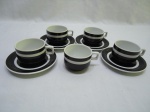 Jogo de 5 xícaras e 4 pires em porcelana Roberto Simões, barra preta. Medindo a xícara 6,5cm x 4,5cm de altura.