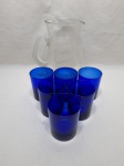 Jarra em vidro incolor com 6 copos de suco em vidro azul cobalto. Medindo a jarra 21,5cm de altura, copo 7cm x 9cm de altura.
