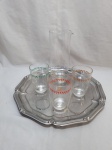 Jarra com 3 copos em vidro incolor e bandeja redonda em aço inox. Medindo a bandeja 35,5cm de diâmetro.