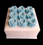 Diferente e graciosa caixa de cera, com tampa de flores em relevo contendo no seu interior, 9 (nove) rosas de velas perfumas. Medidas 16x16x11xm.