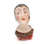 Coleção Half Doll - Cabeça de melindrosa em porcelana com pintura manual. Rosto delicado, lábios em tom coral e sobrancelhas finas. Cabelos pretos em estilo característico da década de 1920, com mecha frontal em espiral. Base numerada 898. 4x2 cm.