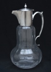 Elegante jarra com alça composta por corpo em vidro transparente canelado, de bojo volumoso . Parte superior apresenta montagens em metal prateado com diversos constrastes .  25x13 cm.