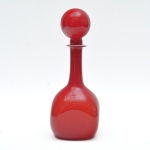 ANOS 50/60 - Afamada garrafa bola em murano, de tom vermelho intenso e uniforme, com interior leitoso. Corpo bojudo assentado sobre base de formato quadrangular. 31x12 cm.