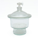 Dessecador em vidro transparente, composto por corpo cilíndrico de paredes espessas, tampa com registro superior em vidro com válvula de controle que permite a criação de vácuo ou controle da atmosfera interna, protegendo amostras. Internamente apresenta prato perfurado removível, uilizado para secagem e conservação de substâncias sensíveis à umidade. Peça de interesse  científico ou decorativo, muito valorizado em coleções de vidraria científica e ambientações de laboratório histórico. Tampa superior com perda e borda bicada. 28x21 cm total