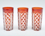 Conjunto de tres copos longos em vidro lapidado,  vermelho rubi, com lapidação geométrica profunda em padrão losangular e faixa vertical. 15x7,5 cm