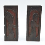 Rústico par de serre livre em madeira maciça, com figuras antropomórficas estilizadas em baixo-relevo,  vestígios de policromia vermelha. Faces laterais entalhadas, uma delas com inscrição P O S. Marcas do tempo. 22x8,5 cm.