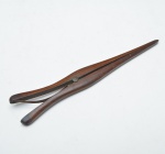 Esticador de luvas em madeira, composto por duas hastes alongadas articuladas por pino central e mola em sua base. Marcas de uso. 26cm.