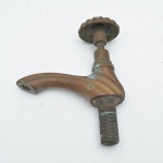 Antiga torneira em bronze fundido de corpo curvo e bica alongada. Acionamento superior por volante em formato canelado. Apresenta rosca inferior para fixação. Marcas do tempo e oxidações. 17x13