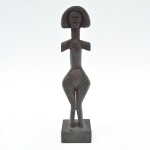 Escultura antropomórfica em madeira,  entalhada em peça única, apresentando figura feminina de forte caráter hierático. 25x7,5x5,5 cm