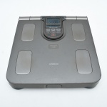 Balança de Bioimpedância OMRON, modelo HBF-514C. Plataforma com eletrodos metálicos para medição corporal. Possui monitor destacável com empunhaduras, visor digital, memória para usuários e funções. Ligando, sem garantias futuras, no estado. 33x30 cm.