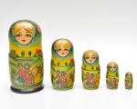 Conjunto composto por cinco bonecas russas articulada confeccionadas em madeira torneada e pintadas à mão. Apresentam decoração com rostos femininos estilizados, detalhes florais e cenas campestres, realçadas por aplicação de douração na região do lenço. Peças encaixáveis entre si. Maior 19x9,5 cm
