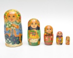 Conjunto composto por cinco bonecas russas articulada confeccionadas em madeira torneada e pintadas à mão. Apresentam decoração com rostos femininos estilizados, detalhes nas mãos de cestos com flores ou frutos em cenas campestres. Peças  encaixáveis entre si. Maior 17x9 cm