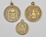 Lote contendo 3 medalhas sacras, em metal dourado. 3,5x3 cm (maior) / 2,5x2 cm (menor).