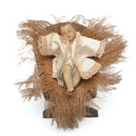 Singela e antiga imagem devocional de Menino Jesus em gesso, peça de cunho religioso e colecionável. Vestimenta de época. Acompanha magedoura. 1 braço colado, no estado. 11x10 cm