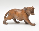 Escultura em madeira maciça, representando tigre com expressão feroz, corpo trabalhado com incisões lineares que sugerem a pelagem rajada. Duas patas com restauro e pequena perda no dente. No estado. 25x13x8 cm.