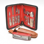 Cutelaria kit portátil de ferramentas, em couro preto, interior forrado em tecido vermelho, contendo peças metálicas variadas.Acompanha canivete com estojo em couro. Marcas de uso. 14x12 cm (estojo).